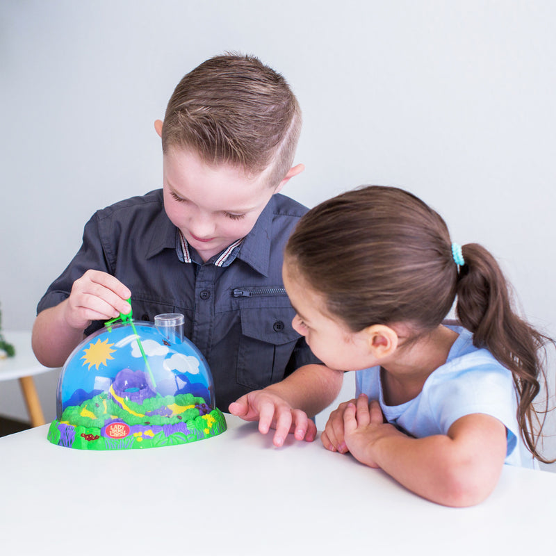 Two children viewing ladybirds in a colourful BugLand insect habitat, one is inserting a pipette to provide drinking water